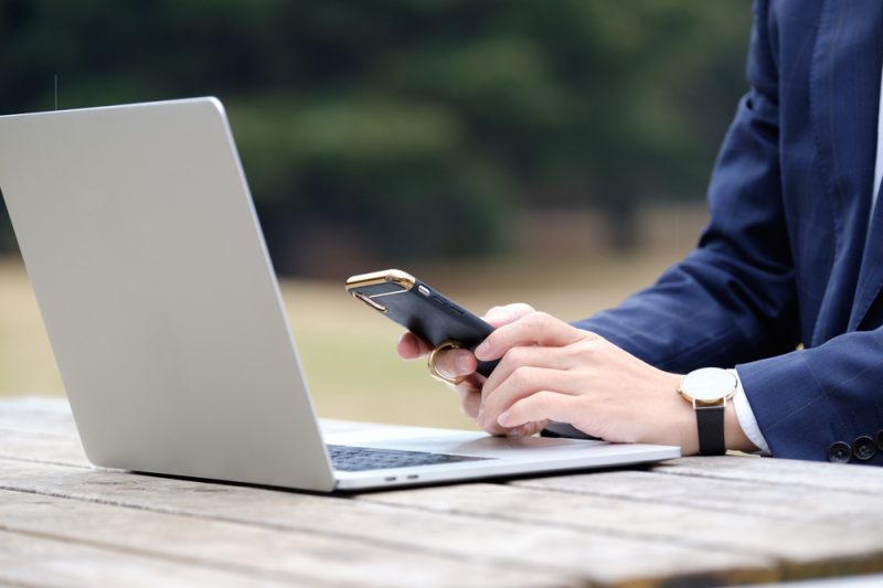 Male businessman operating a smartphone outdoors