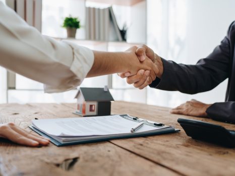 同銀行のモーゲージ・オフィサーは、住宅投資ローン契約に署名した後、顧客と握手を行い、顧客を祝福します。