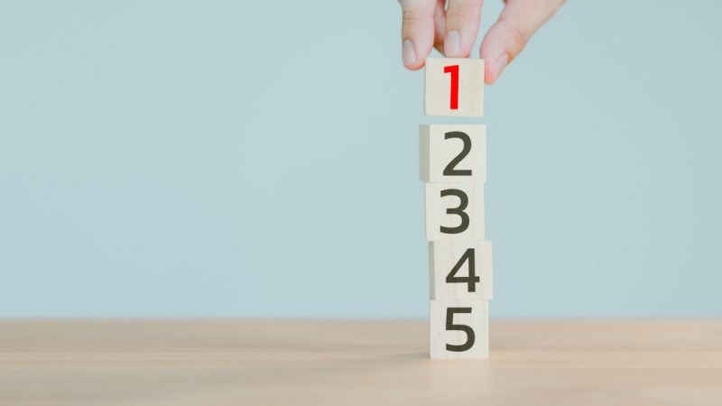 Hand,Putting,A,Wooden,Cube,With,Number,1,On,Wood