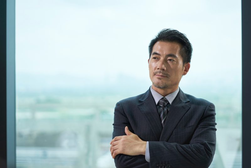 Portrait,Of,A,Mature,Asian,Business,Man,Standing,By,Window
