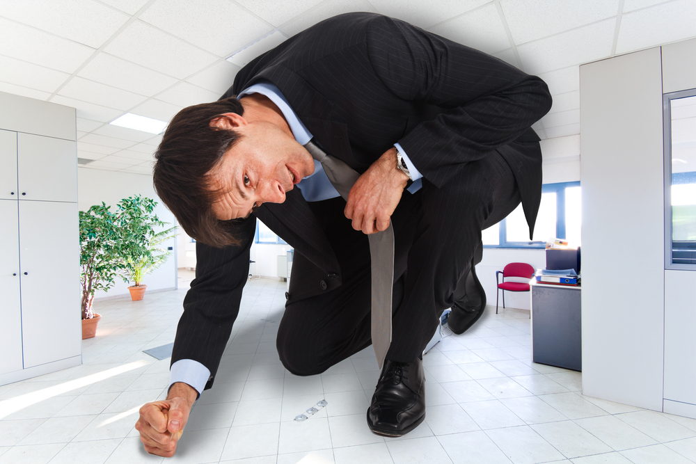 小さなオフィスに押し込められているスーツの男性