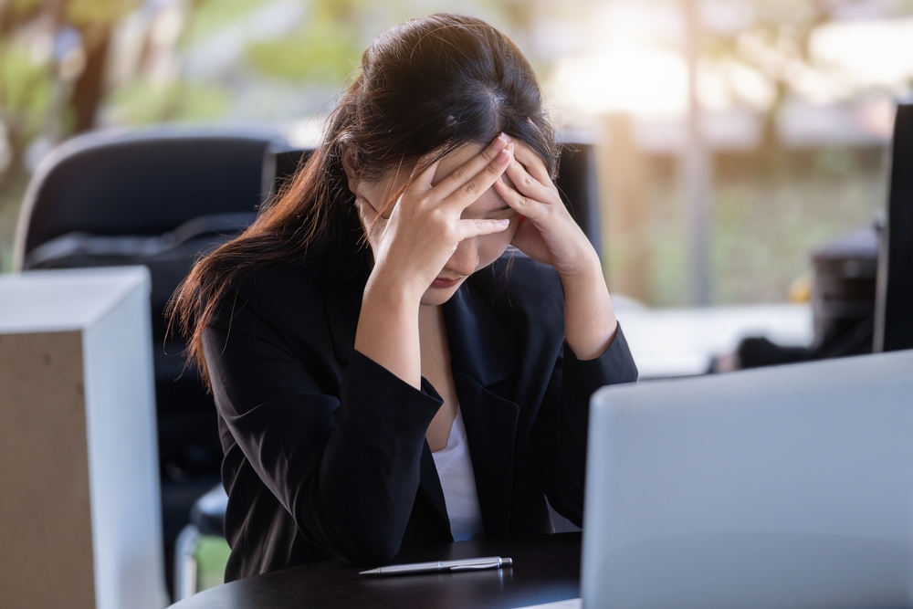 PCの前で頭を抱えている女性