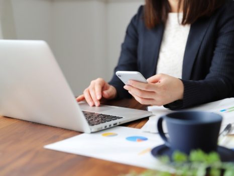 パソコンとスマホを操作しているスーツ姿の女性