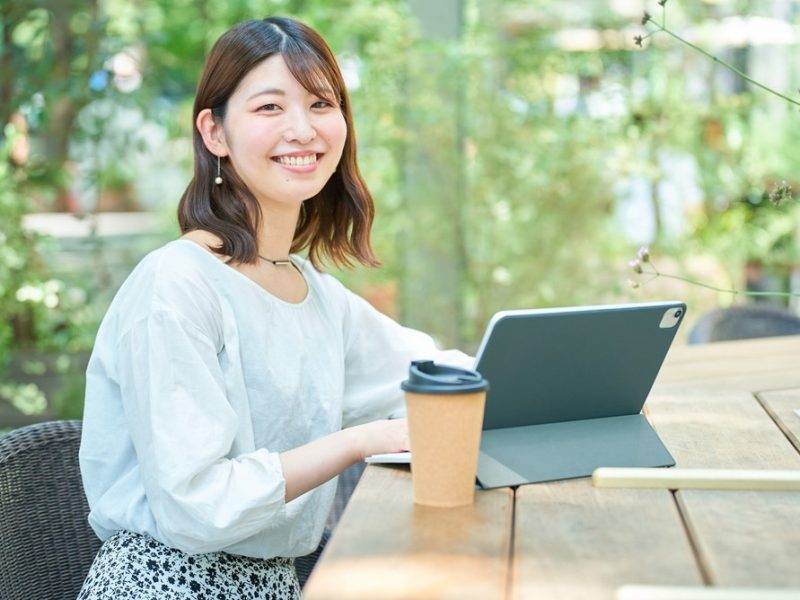 街角でタブレットPCを操作する笑顔の女性